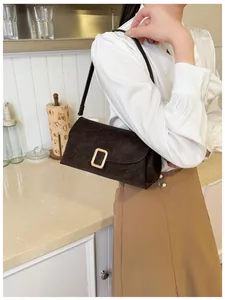 Detail of dark brown suede shoulder bag with golden buckle in lifestyle setting
