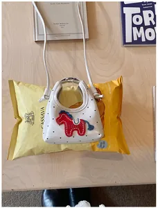 Dettaglio della mini borsa bianca a pois neri con ricamo a forma di cavallo rosso su legno