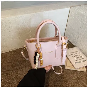 Detail der rosa Kunstleder-Beuteltasche mit Goldbeschlägen und bunter Perlenverzierung