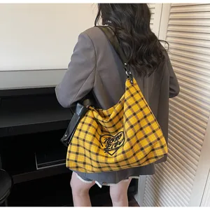 Detail of yellow checkered tote bag with heart embroidery and black leather strap
