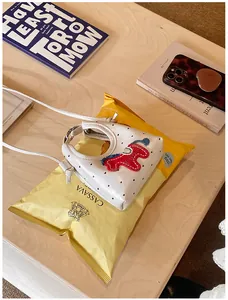 Dettaglio di una mini borsa bianca a pois con ricamo a forma di pony e tracolla sottile