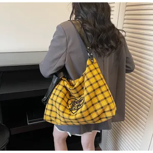 Macro detail of yellow plaid tote bag with heart embroidery and black leather strap