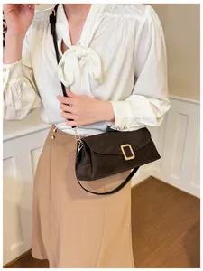 Close-up of retro dark brown square crossbody bag with elegant gold metal buckle detail