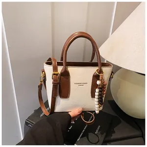 Detail der creme-braunen PU-Leder Umhängetasche mit dekorativem Perlenanhänger