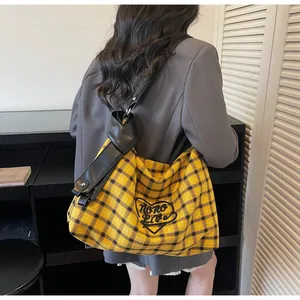 Detail of adjustable black leather strap and yellow plaid canvas on the hobo tote bag