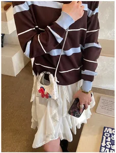 Dettaglio della mini borsa bianca con toppa a forma di pony rosso e doppi manici