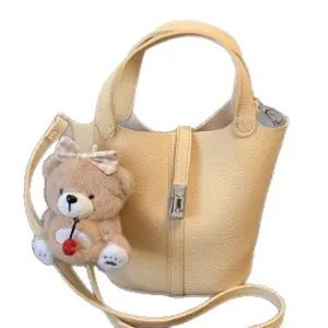 Beige lederen bucket bag met handvatten en schattige pluche beer-accessoire