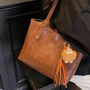 Brown vintage faux leather tote bag with furry monster charm shown on model