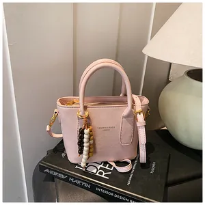 Detailansicht der rosa PU-Lederbeuteltasche mit Perlenanhänger und goldener Hardware