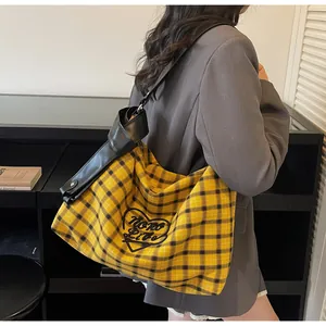 Detail of checkered tote bag featuring black heart embroidery and premium wide leather strap