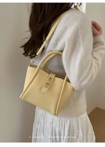 Detailansicht der cremegelben Beuteltasche mit Litschi-Muster und goldenem Drehschloss
