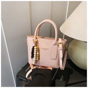Detail der weichen rosa Handtasche mit bunter Perlenquaste und Goldbeschlägen