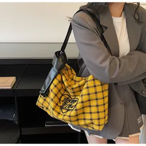 Detail of yellow plaid hobo bag with black leather shoulder strap and decorative knot