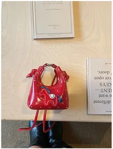 Vista dall'alto di una mini borsa rossa con stampa a cuore e ricamo pony su legno