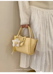 Detail der hellgelben Beuteltasche mit Litschi-Muster, Goldschloss und Bärchen