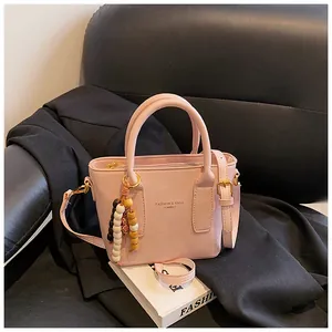 Detailaufnahme der rosa PU-Leder Eimertasche mit Perlenanhänger und goldener Hardware