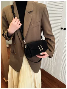 Detail of a black square crossbody bag with gold buckle on a brown blazer outfit
