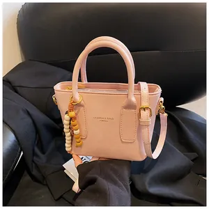 Detail der rosa Handtasche aus PU-Leder mit Holzperlenanhänger und goldenem Reißverschluss