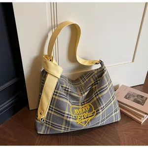 Detail of grey plaid canvas tote bag featuring yellow leather knotted strap and heart embroidery