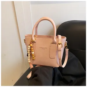 Nahaufnahme der rosa Beuteltasche mit YIMING-Logo und dekorativem Holzperlen-Anhänger
