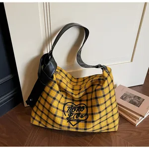 Detail of yellow plaid tote bag with NORO Live heart embroidery and black leather strap