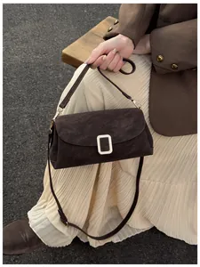 Detail of a dark brown suede square bag featuring a stylish silver metal buckle closure