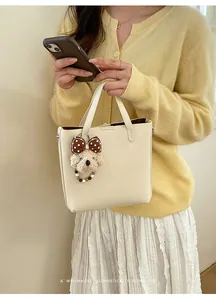Detail der cremefarbenen Mini-Tragetasche mit Plüschwelpen-Anhänger und Retro-Design