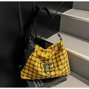 Detail of yellow plaid tote bag with heart embroidery and stylish black knotted strap