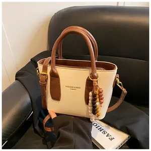 Detailansicht der Retro-Handtasche in Creme mit braunem Rand und buntem Holzperlen-Anhänger