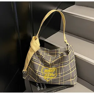 Detail of yellow heart embroidery on plaid tote bag with stylish knotted leather strap