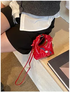 Dettaglio macro della mini borsa rossa a pois con ricamo di un piccolo pony