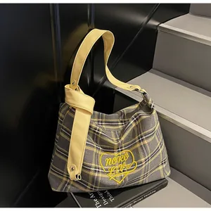 Detail of checkered tote bag with heart embroidery and yellow leather knotted shoulder strap