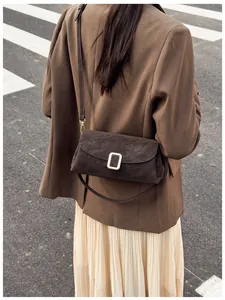 Detail view of a vintage dark brown crossbody bag with a square metal buckle decoration