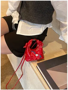 Dettaglio mini borsa in vernice rossa a pois bianchi con ricamo a cavallo