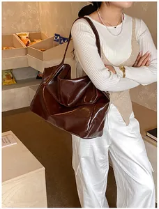 Detail einer großen dunkelbraunen Ledertasche mit weicher Textur und geräumigem Seitenprofil