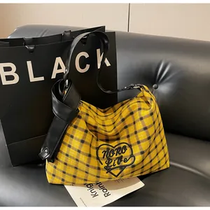 Detail of yellow plaid canvas tote with black heart embroidery and knotted faux leather strap
