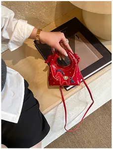 Dettaglio della mini borsa rossa a pois con ricamo a forma di pony e pelle lucida
