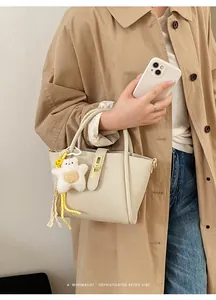 Beige Eimertasche mit Litschi-Muster, Goldschloss und Plüschstern am Trenchcoat