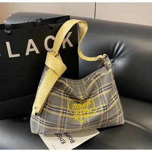 Detail of grey and yellow checkered tote bag with heart embroidery on a black sofa