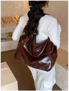 Detail der braunen Hochglanz-PU-Schultertasche mit Vintage-Nieten am Schultergurt-Design