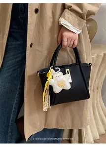 Detail der schwarzen Handtasche mit Litschi-Maserung, Goldschloss und Stern-Anhänger