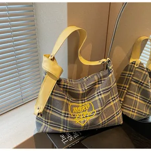 Detail of checkered tote bag with heart embroidery and yellow knotted shoulder strap