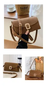 Detailed view of brown matte leather square bag with gold buckle and adjustable strap
