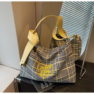 Detail of checkered hobo bag with yellow heart embroidery and knotted leather handle
