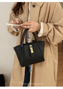 Detail der schwarzen Handtasche aus Leder mit Litschistruktur und goldenem Drehverschluss