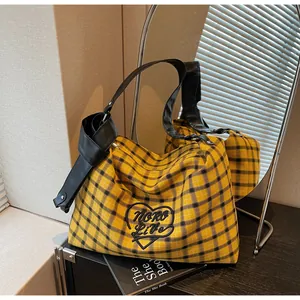 Detail of yellow plaid tote bag with heart embroidery and stylish knotted black strap