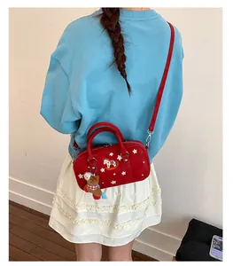 Detail of red canvas Boston bag with star print and cute bear pendant on a model