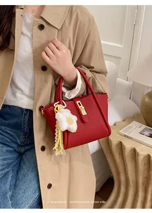 Detail der roten Beuteltasche aus genarbtem Leder mit Goldschloss und Blumenanhänger