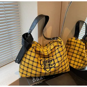 Detailed view of yellow plaid tote bag with black heart embroidery and adjustable leather strap