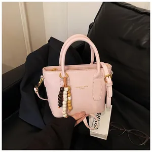 Detail der rosa PU-Leder Beuteltasche mit Holzperlen-Quaste und goldenem Mode-Text